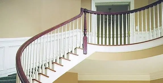 Curved staircase with a wood handrail and white balusters