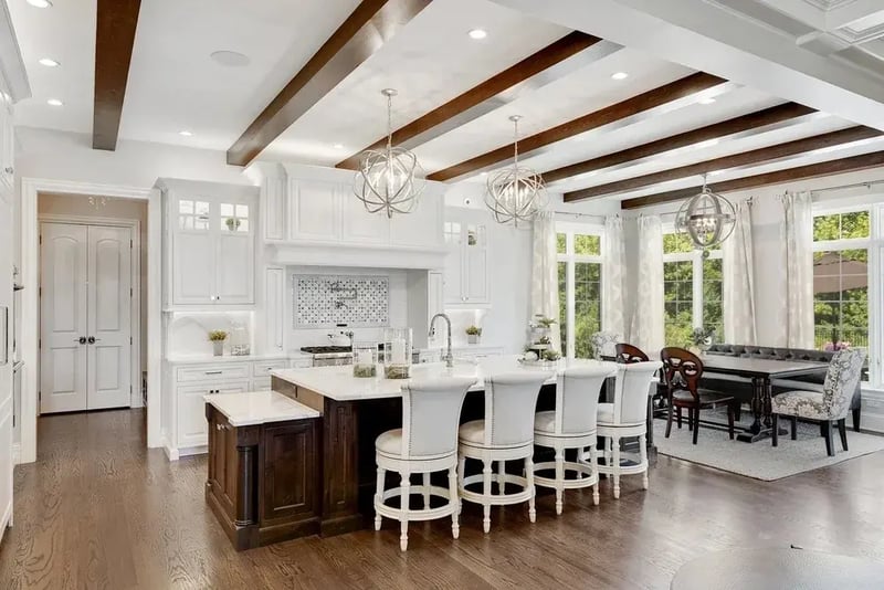 White kitchen with exposed wood ceiling beams and a large island