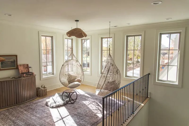 Sunlit landing with tall windows and two hanging chairs