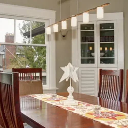 Dining room with large windows beside a glass-front cabinet